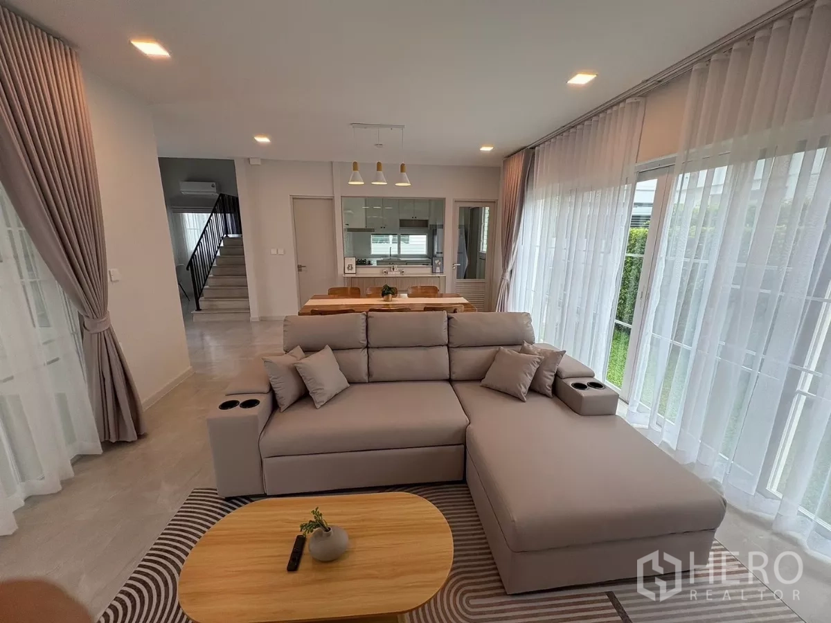 Detached House for rent or sale in Bang Phli, Samut Prakan - Living room view to dining area, staircase and glass-walled kitchen.