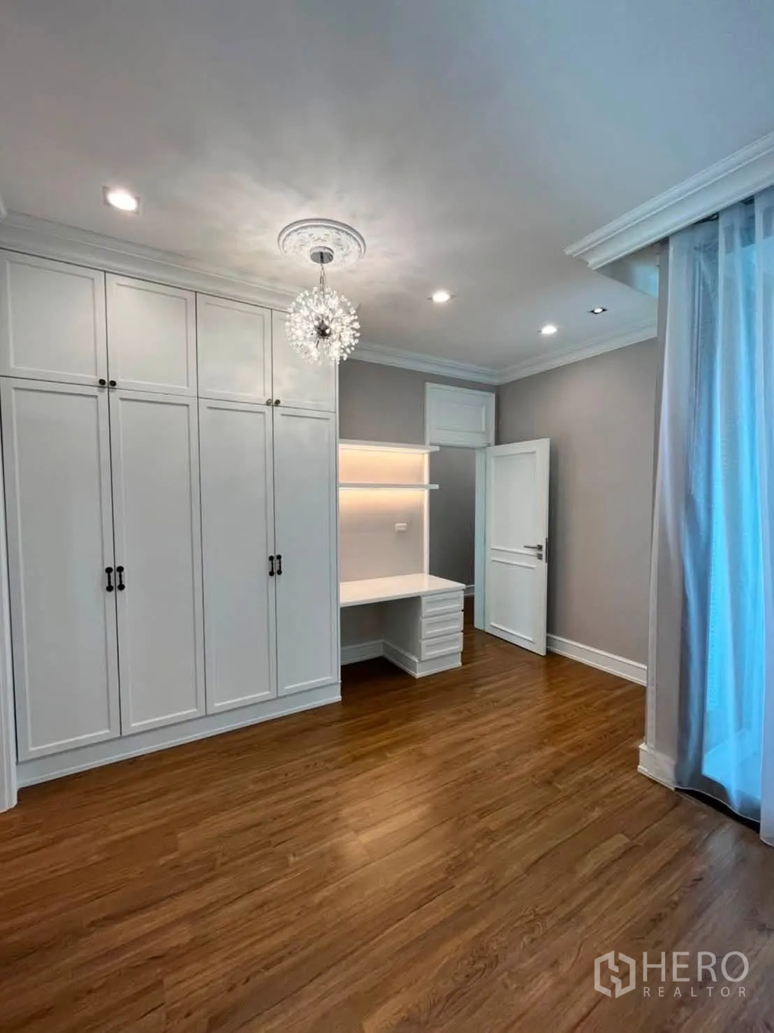 Townhouse for rent in Lat Phrao, Bangkok - Spacious bedroom with built-in wardrobes, desk and chandelier.