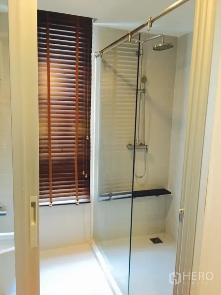 公寓 出租或出售在Khlong Toei, Bangkok - 现代浴室，玻璃干湿分离淋浴间，顶喷花洒与长凳，旁有百叶窗。