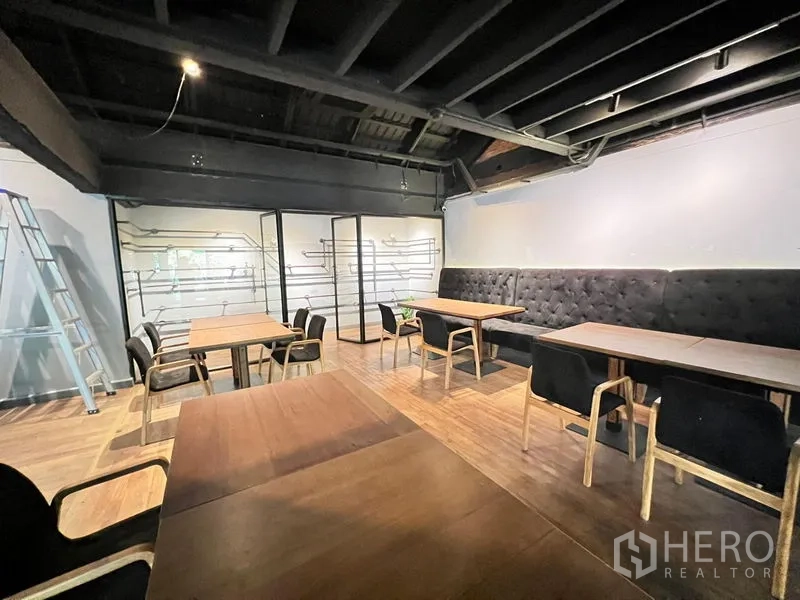 零售空间 出租在Bangkok - 宽敞用餐区，软包长椅、木地板与外露顶。