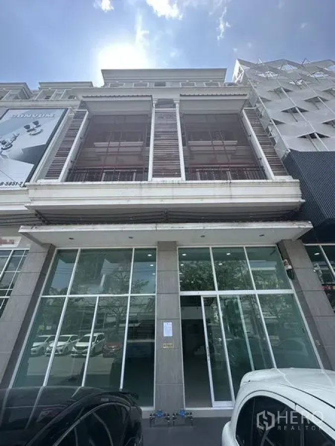 带办公室的家 出租在Bang Na, Bangkok - 多层建筑正立面，大型玻璃入口与前方停车位。