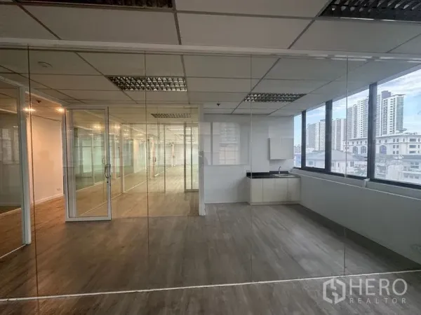 办公空间 出租在Din Daeng, Bangkok - 开放式办公区带玻璃隔断与茶水间，外侧为城市景观窗。