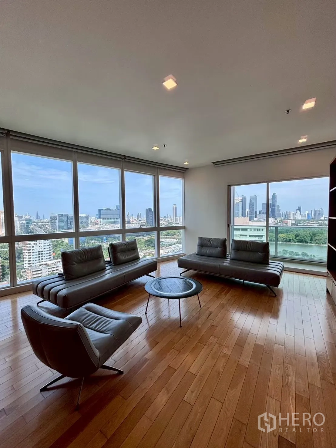 Condominium for rent in Khlong Toei, Bangkok - Living room with wide windows offering skyline and greenery views over the city.