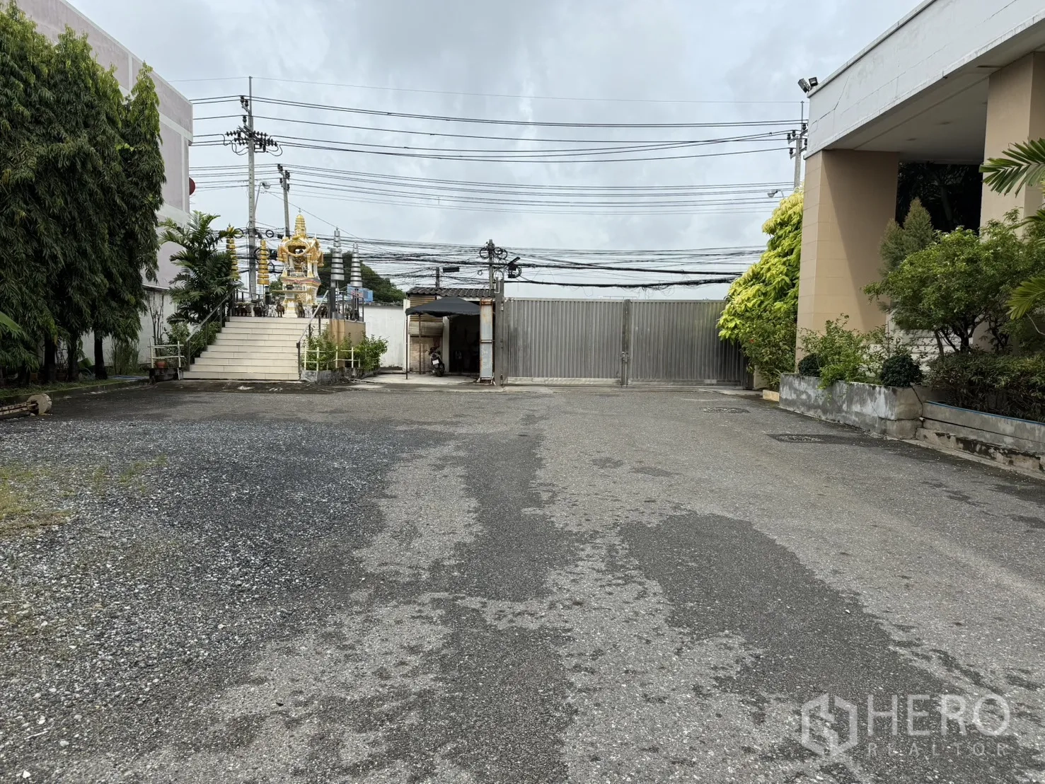 Factory for rent in Bang Phli, Samut Prakan - Wide driveway within the compound leading to a secure sliding metal gate with landscaping.