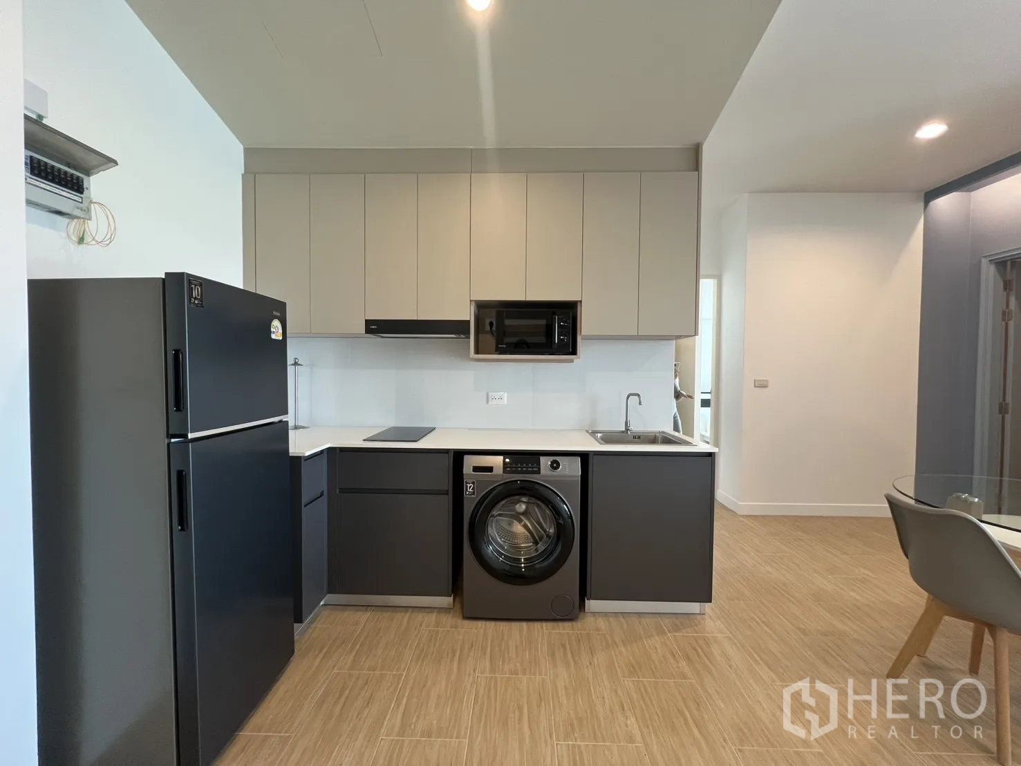 Condominium for rent in Bang Kapi, Bangkok - Modern L-shaped kitchen with matte cabinets, fridge, washer, microwave, and sink.