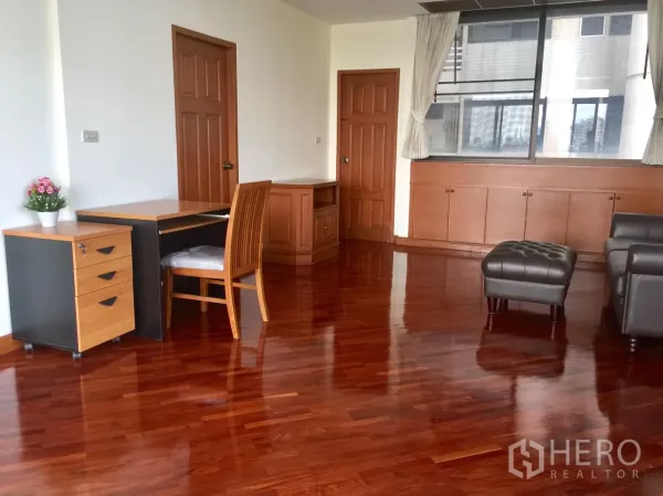 คอนโด ให้เช่าในKhlong Toei, Bangkok - ห้องนั่งเล่นกว้าง พื้นไม้เงา โต๊ะทำงานและโซฟาหนัง ริมหน้าต่างบานใหญ่