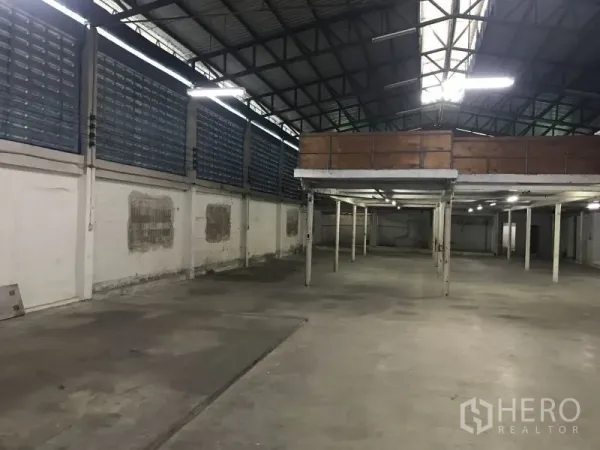 Factory for rent or sale in Krathum Baen, Samut Sakhon - Open production floor showing mezzanine storage deck, skylight and ventilated louvered walls.
