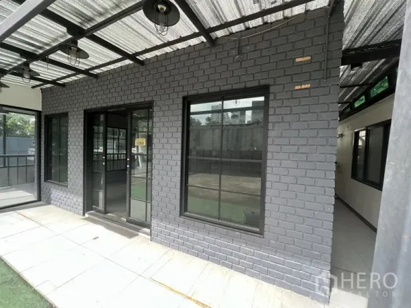 零售空间 出租在Watthana, Bangkok - 灰砖店面，黑框大窗与双开玻璃门，带雨棚。