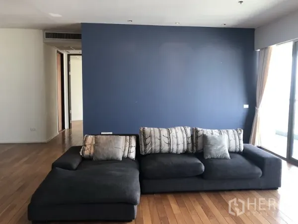 คอนโด ให้เช่าในKhlong Toei, Bangkok - ห้องนั่งเล่นสว่าง ผนังสีน้ำเงิน โซฟารูปตัวแอล พร้อมประตูระเบียง พื้นไม้