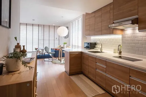 คอนโด ให้เช่าหรือขายในPathum Wan, Bangkok - ครัวบิวท์อินโทนไม้กับผนังอิฐขาว เชื่อมต่อพื้นที่นั่งเล่นสว่างในคอนโดปทุมวัน