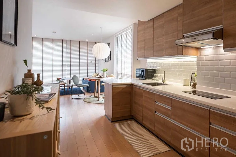 คอนโด ให้เช่าหรือขายในPathum Wan, Bangkok - ครัวบิวท์อินโทนไม้กับผนังอิฐขาว เชื่อมต่อพื้นที่นั่งเล่นสว่างในคอนโดปทุมวัน
