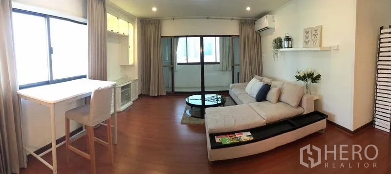 คอนโด ให้เช่าหรือขายในDin Daeng, Bangkok - พื้นที่นั่งเล่นพร้อมโซฟาตัวแอล โต๊ะกลางทรงกลม และประตูกระจกบานเลื่อนไปยังระเบียง.