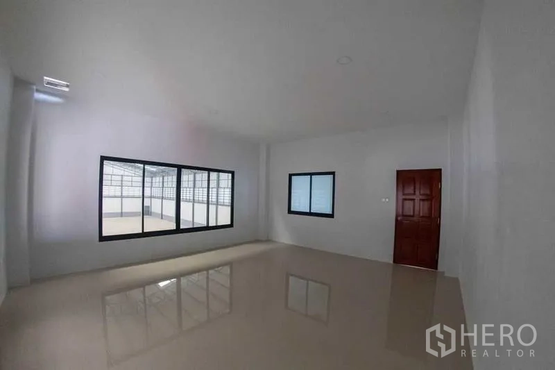 Warehouse for sale in Krathum Baen, Samut Sakhon - Spacious tiled office room with large windows and a wooden door.