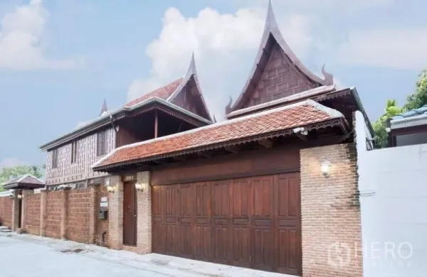 独立式住宅 出租在Bang Na, Bangkok - 临街立面，高大木门与砖墙，尖顶泰式屋脊。