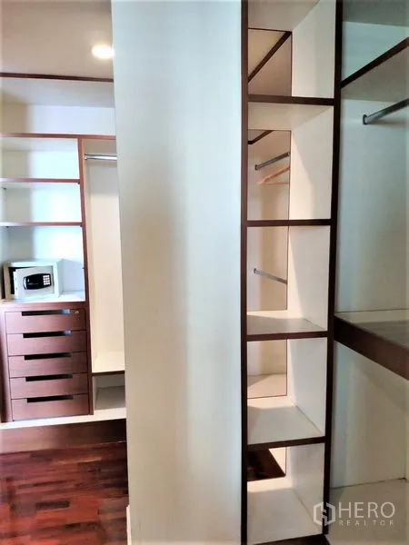 Condominium for rent in Bang Rak, Bangkok - Walk-in closet with built-in shelves, drawers, hanging rails and an in-room safe.