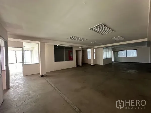 Warehouse for rent in Suan Luang, Bangkok - Wide open-plan floor with interior glass partitions, concrete floor and fluorescent lighting.