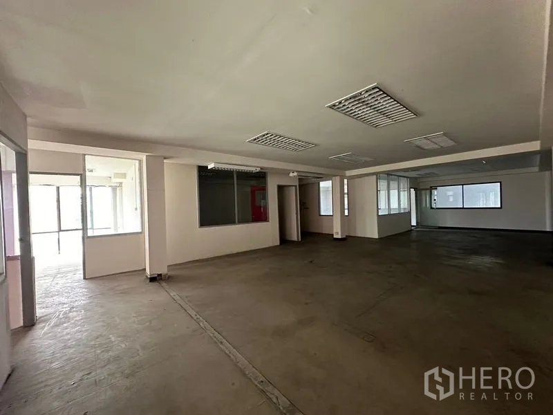 Warehouse for rent in Suan Luang, Bangkok - Wide open-plan floor with interior glass partitions, concrete floor and fluorescent lighting.