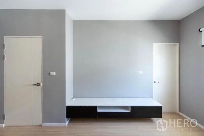 Townhouse for rent or sale in Watthana, Bangkok - Spare room with TV console, two interior doors and neutral grey walls.