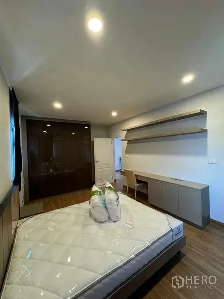 Detached House for rent in Don Mueang, Bangkok - Furnished bedroom with bed, wall shelves, desk and glossy built-in wardrobe.