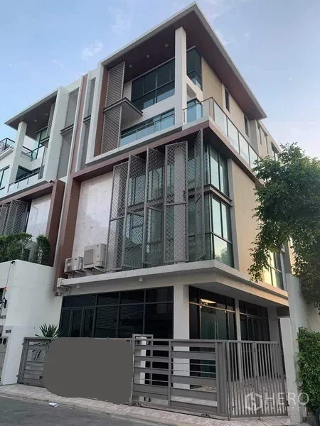 Townhouse for rent or sale in Yan Nawa, Bangkok - Corner view of contemporary townhouse with glass walls, balcony and secure gate.