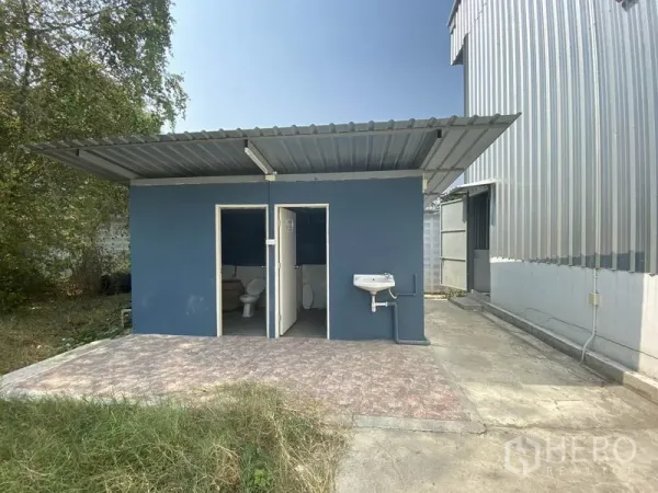 货栈 出租在Prawet, Bangkok - 仓库旁独立蓝色卫生间建筑，两个厕间并配有室外洗手盆。