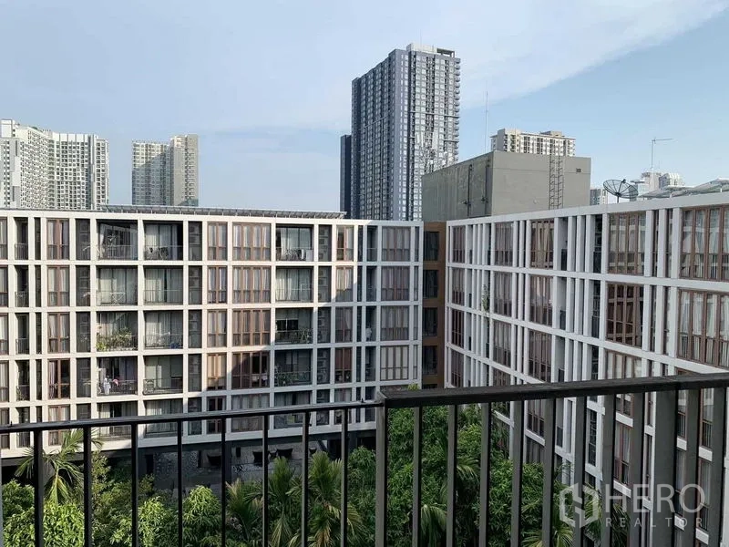 Condominium for rent or sale in Watthana, Bangkok - Balcony view over a modern courtyard condo with city skyline and greenery.