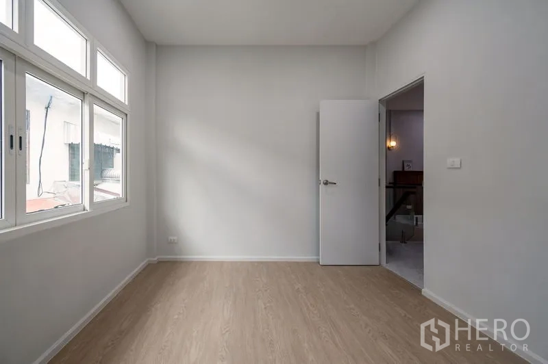 Townhouse for sale in Din Daeng, Bangkok - Sunlit bedroom with large windows and light wood flooring.