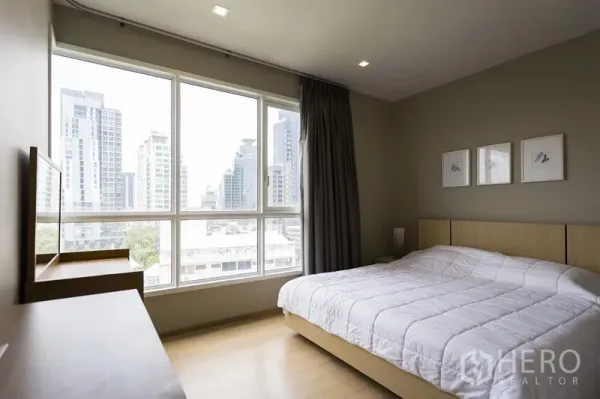 คอนโด ให้เช่าในWatthana, Bangkok - ห้องนอนหน้าต่างบานใหญ่เห็นวิวสกายไลน์ เตียงควีน และเฟอร์นิเจอร์ลายไม้โทนอ่อน