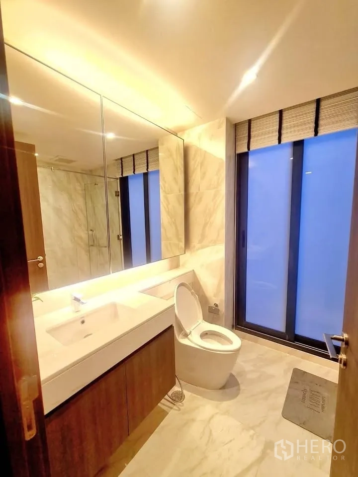 Townhouse for rent or sale in Watthana, Bangkok - Bathroom with marble-look walls, large vanity, and frosted window.