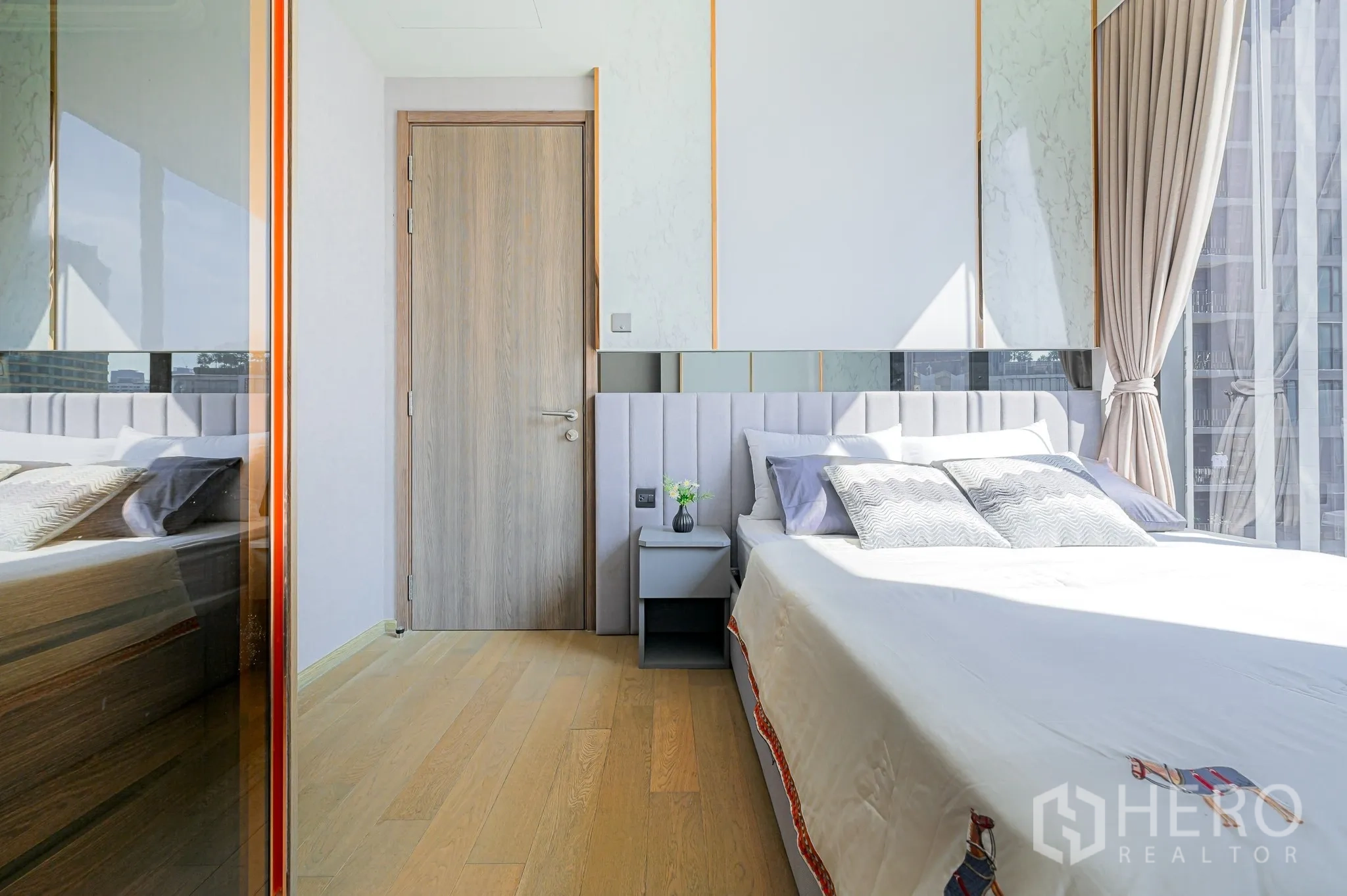 公寓 for rent in Watthana, Bangkok - 明亮卧室，浅色木地板、软包床头与床边柜，配落地窗与城市景观。