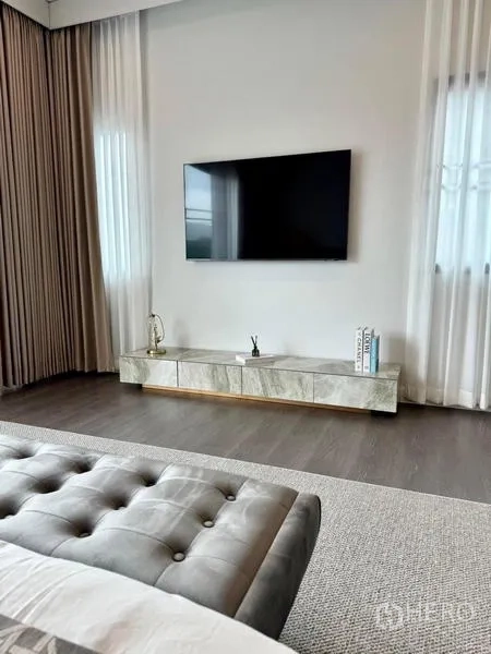 Detached House for rent or sale in Bang Kapi, Bangkok - Master bedroom TV wall with low cabinet and wood flooring.