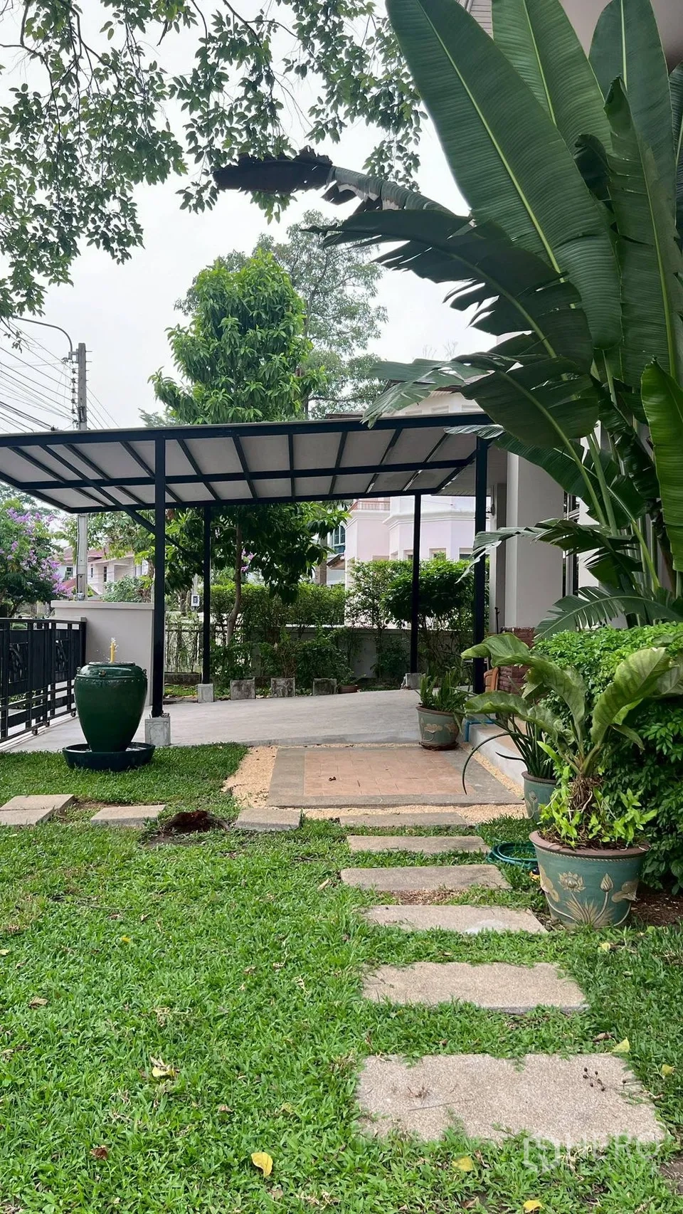 Detached House for rent in Lat Krabang, Bangkok - Landscaped front yard with stepping-stone path, tropical plants and covered carport.