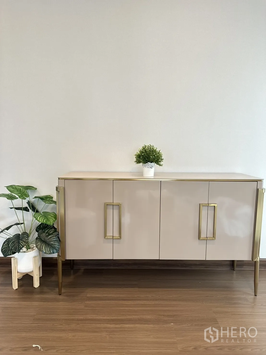 独立式住宅 出租或出售 - 极简边柜，金色拉手与绿植，背景为素色墙面。