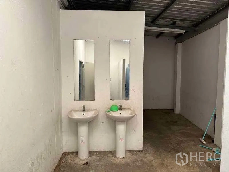Factory for rent or sale in Bang Phli, Samut Prakan - Factory wash area with two pedestal sinks and mirrors next to restroom stalls.