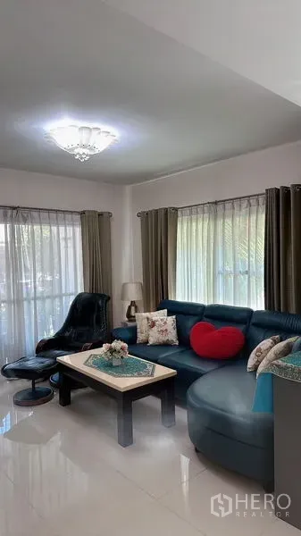 Detached House for rent in Bang Phli, Samut Prakan - Bright living room with a blue sectional sofa, recliner, and sheer curtains.