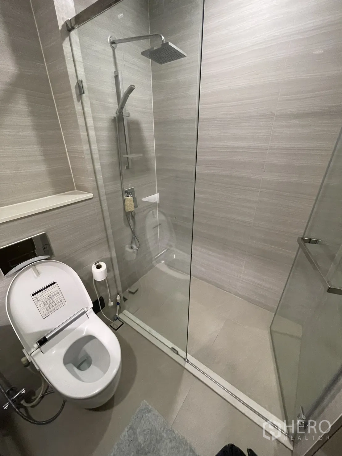 Condominium for rent in Watthana, Bangkok - Modern bathroom with glass shower enclosure, rain shower, and toilet.
