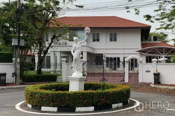 独立式住宅 出租在Bang Phli, Samut Prakan - 从景观环岛处看到的房子正面，设有经典雕像与庭院大门。