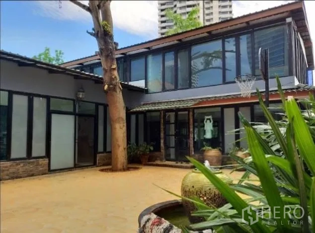 บ้าน ให้เช่าในKhlong Toei, Bangkok - ลานกลางบ้านเดี่ยวสมัยใหม่ ผนังกระจก มีต้นไม้ใหญ่และวิวตึกเมือง