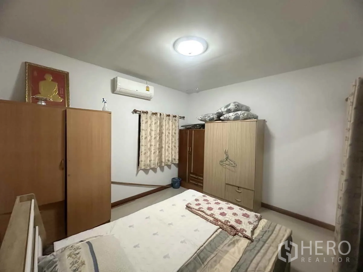 独立式住宅 出售在Pathum Thani - 卧室另一角，衣柜、床与窗户一览。