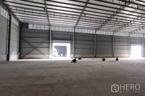 货栈 出租在Bang Bo, Samut Prakan - 宽敞空旷的仓库大厅，混凝土地坪，明亮的卷闸门开口。