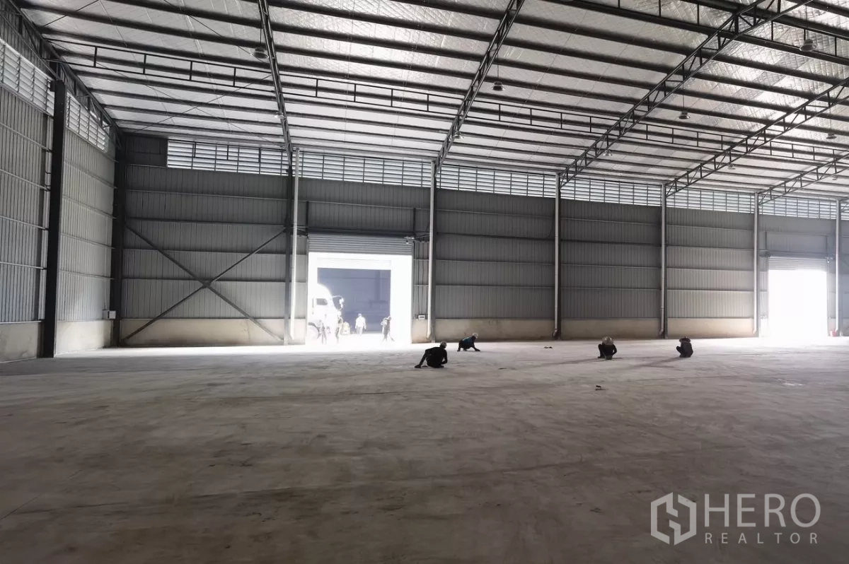 货栈 出租在Bang Bo, Samut Prakan - 宽敞空旷的仓库大厅，混凝土地坪，明亮的卷闸门开口。