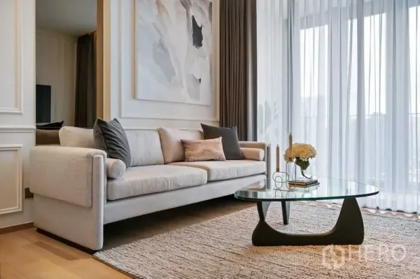 公寓 出租或出售在Khlong Toei, Bangkok - 通罗公寓客厅，米色沙发、玻璃茶几与落地窗纱帘。