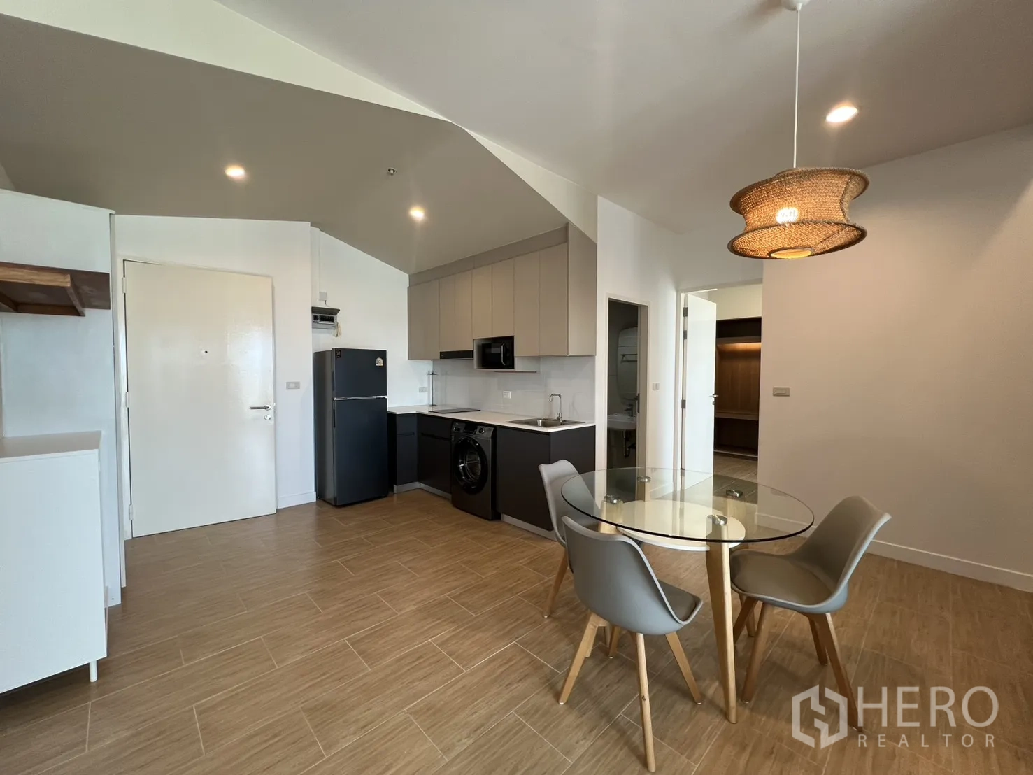 Condominium for rent in Bang Kapi, Bangkok - Kitchen with four-seat glass dining table under pendant lighting.