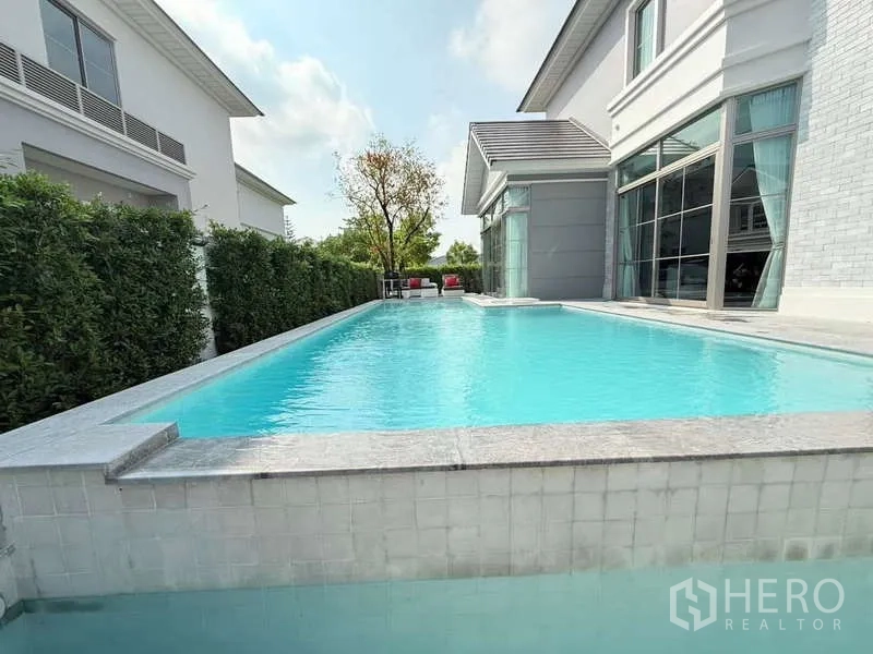 Detached House for rent or sale in Bang Phli, Samut Prakan - Private swimming pool beside the house with clear blue water, tiled edge and tall hedges for privacy.