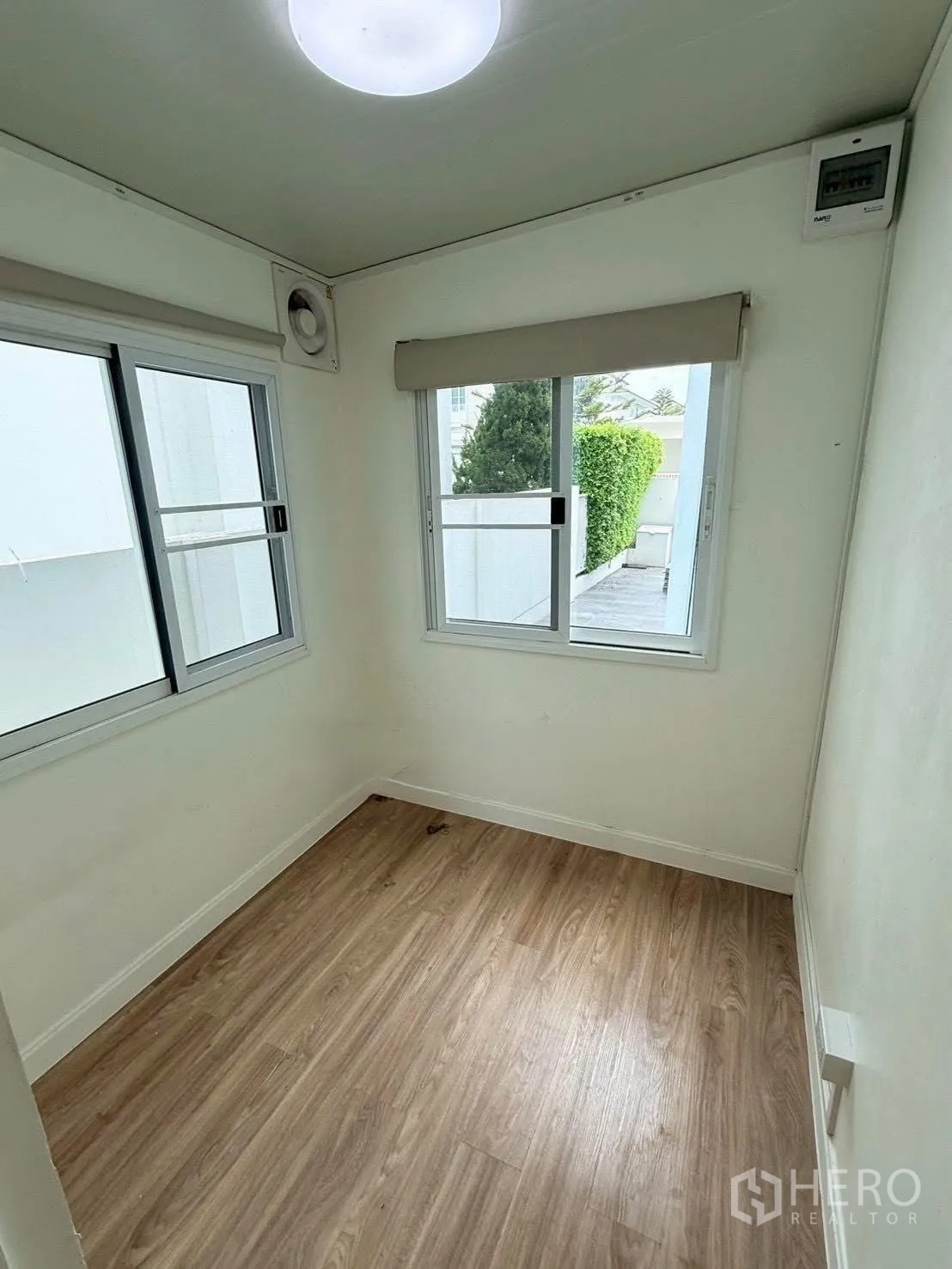 Detached House for rent in Bang Phli, Samut Prakan - Small bright room with two windows and wood-look flooring.