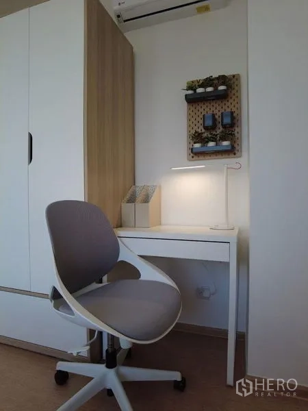 Condominium for sale in Watthana, Bangkok - Compact study corner with white desk, ergonomic chair, and built-in wardrobe.