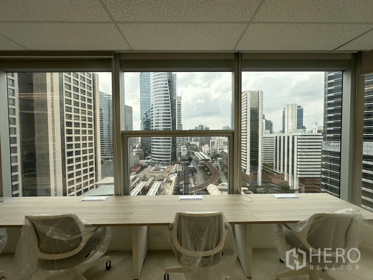 ออฟฟิศ for rent in Sathon, Bangkok - มุมมองเมืองจากโต๊ะริมหน้าต่าง เห็นอาคารสำนักงานและแนวรางรถไฟ