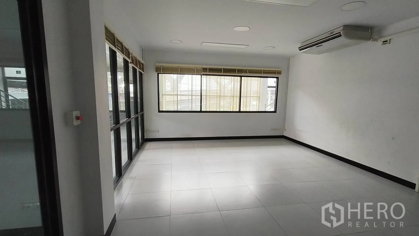 Office Space for rent in Khlong Toei, Bangkok - Corner office with glass walls and blinds overlooking the lobby.
