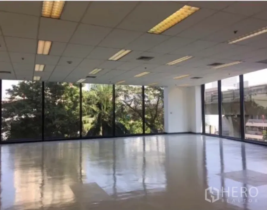 办公空间 出租在Phaya Thai, Bangkok - Ari 明亮转角办公室，落地窗、抛光地面与吊顶灯，窗外绿景，临近捷运。