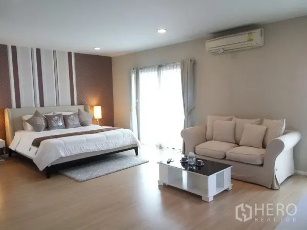 Condominium for rent or sale in Pathum Wan, Bangkok - Spacious master bedroom with king bed, sofa seating, coffee table, and balcony door with sheer curtains.